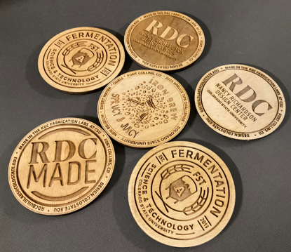 Laser engraved 4-inch-diameter plywood coasters. Examples of artwork options.